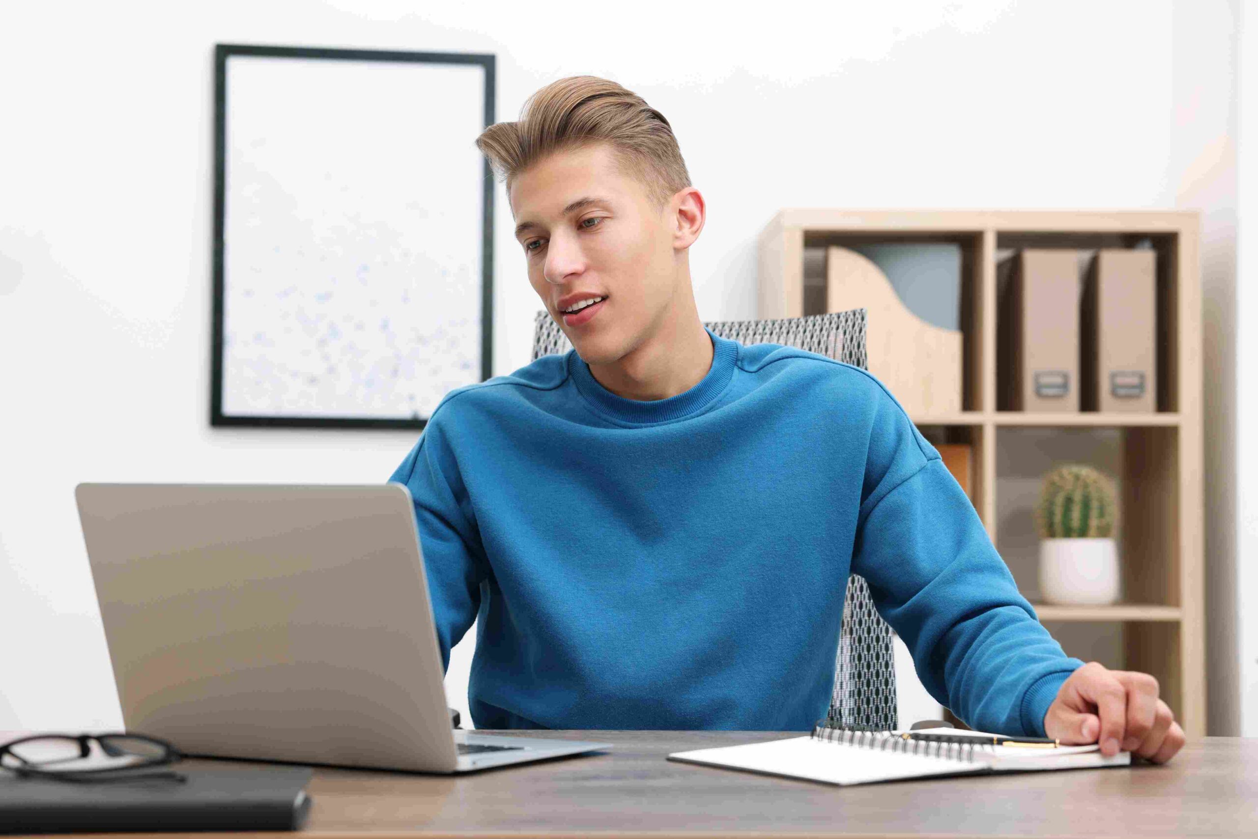 Mladić radi na laptopu za radnim stolom